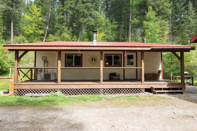view of front of home featuring metal roof, a porch, and a forest view