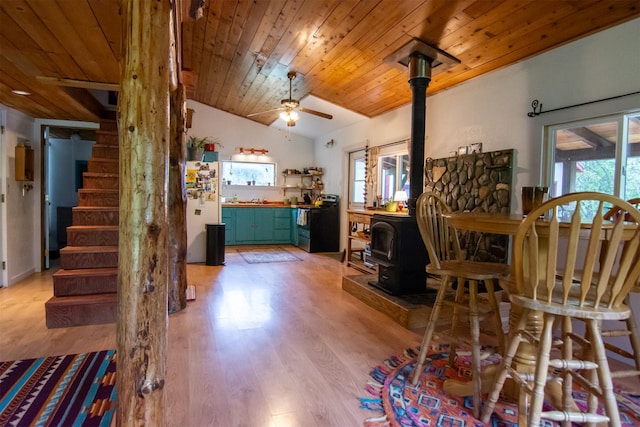 interior space with a wood stove, lofted ceiling, wood ceiling, and light wood-style floors