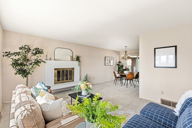 living area with a brick fireplace, a chandelier, visible vents, and carpet floors