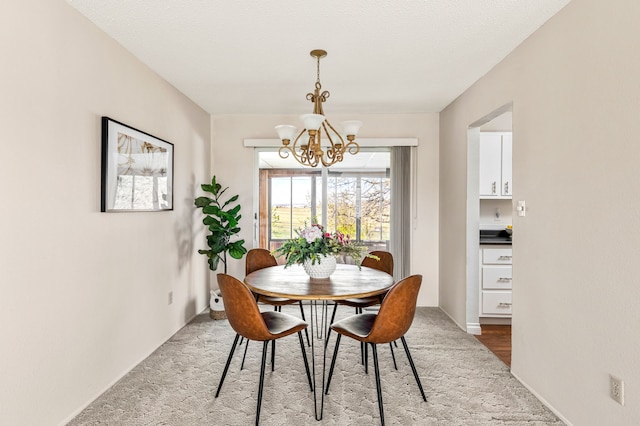 dining space featuring baseboards, a notable chandelier, and carpet