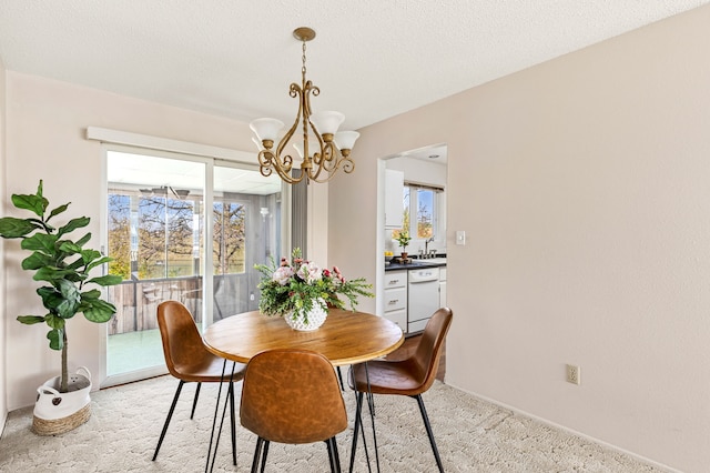 dining area featuring light colored carpet, a chandelier, baseboards, and a healthy amount of sunlight