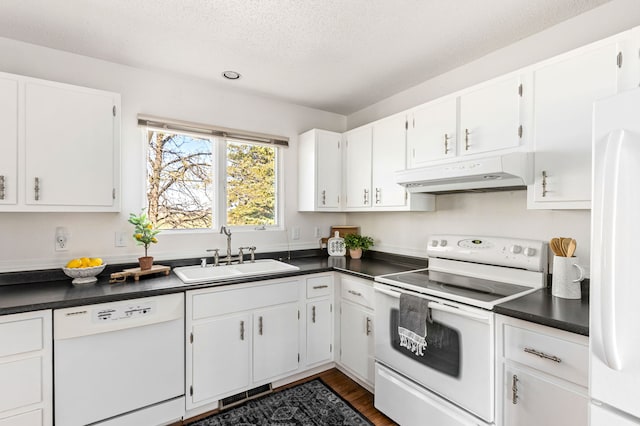 kitchen with under cabinet range hood, white appliances, a sink, and dark countertops
