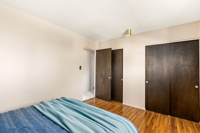 bedroom with two closets and wood finished floors
