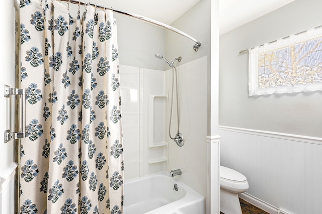 full bath featuring toilet, a wainscoted wall, and shower / bath combo
