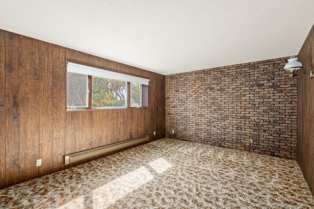 carpeted empty room featuring brick wall, a baseboard radiator, wooden walls, and a textured ceiling