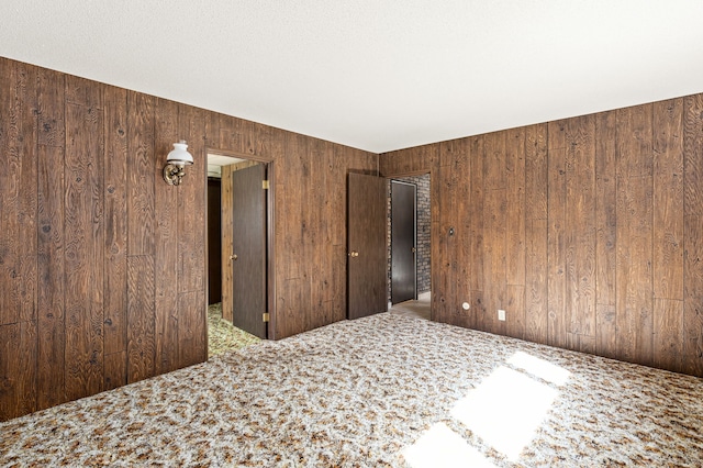 unfurnished bedroom featuring wooden walls and carpet