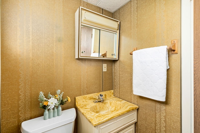 bathroom featuring wallpapered walls, toilet, and vanity