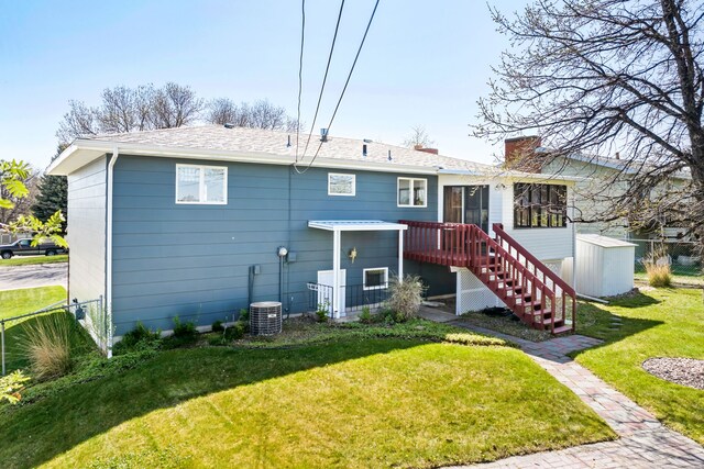 rear view of property featuring an outdoor structure, a storage unit, stairway, a chimney, and a lawn