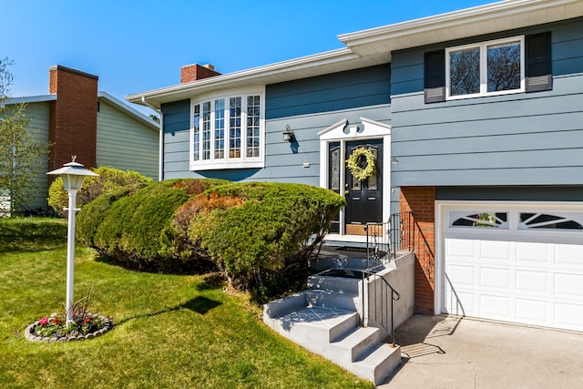 split foyer home with a chimney, brick siding, a front lawn, and an attached garage