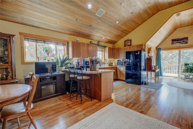 45 Bay Rd, Whitehall, MT 59759 - kitchen featuring freestanding refrigerator, light wood finished floors, stainless steel microwave, a peninsula, and tasteful backsplash