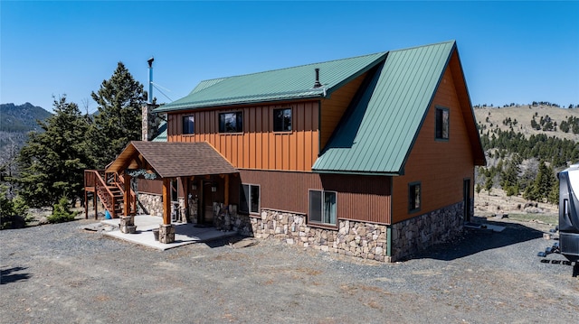 45 Bay Rd, Whitehall, MT 59759 - view of front of house featuring stone siding, a patio, stairway, metal roof, and board and batten siding