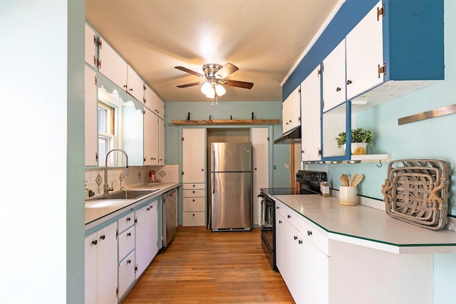 kitchen featuring a sink, stainless steel appliances, ceiling fan, light wood finished floors, and light countertops