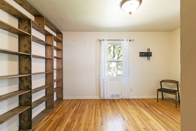 unfurnished room featuring visible vents, wood finished floors, and baseboards