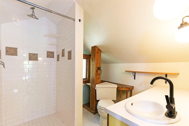 bathroom with vanity, toilet, vaulted ceiling, and a tile shower