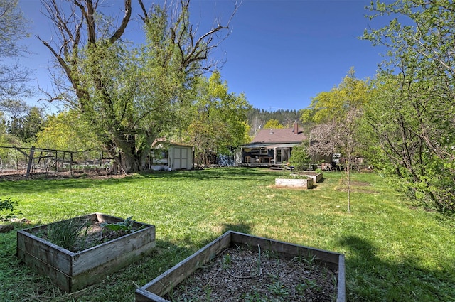 view of yard with a vegetable garden, an outbuilding, a storage shed, and fence