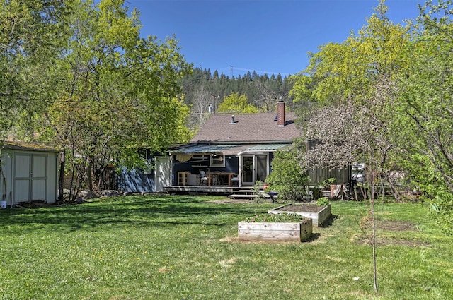 rear view of property with a chimney, an outdoor structure, a shed, a vegetable garden, and a yard