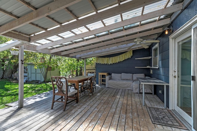 deck featuring ceiling fan, an outbuilding, outdoor dining space, and a storage unit
