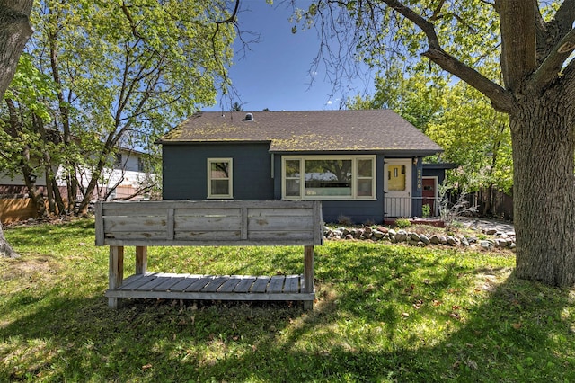 exterior space featuring a front yard, roof with shingles, and fence