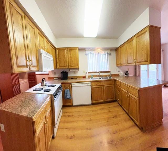 105 Garden Dr Unit D, Kalispell, MT 59901 - kitchen featuring white appliances, a peninsula, light wood finished floors, brown cabinets, and light countertops