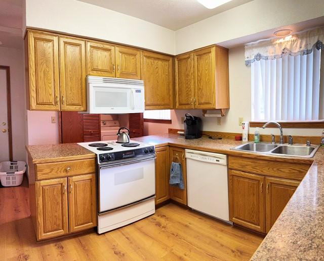 105 Garden Dr Unit D, Kalispell, MT 59901 - kitchen with light wood-style floors, brown cabinetry, a sink, and white appliances