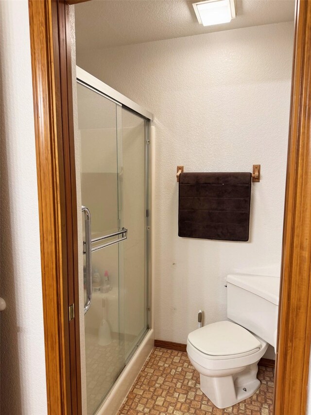 105 Garden Dr Unit D, Kalispell, MT 59901 - bathroom featuring a stall shower, baseboards, and toilet