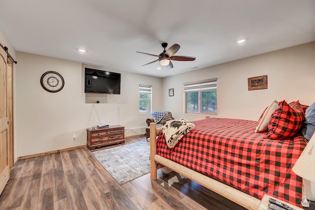 617 Mcclellan Creek Rd, Clancy, MT 59634 - bedroom featuring a barn door, wood finished floors, recessed lighting, baseboards, and ceiling fan