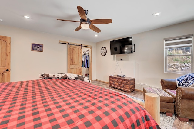 617 Mcclellan Creek Rd, Clancy, MT 59634 - bedroom with a barn door, wood finished floors, recessed lighting, and a ceiling fan