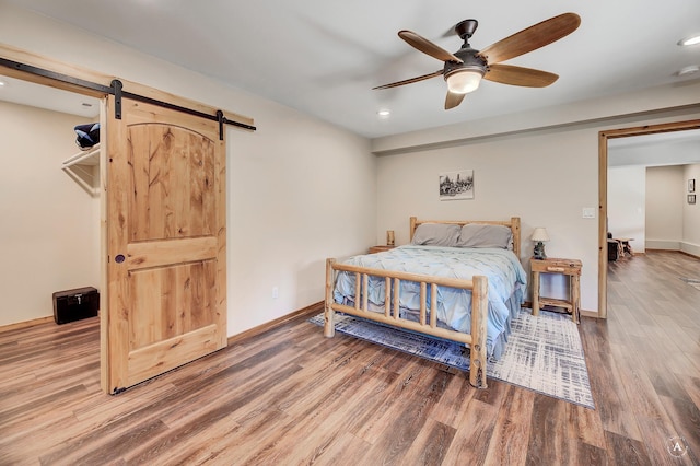 617 Mcclellan Creek Rd, Clancy, MT 59634 - bedroom featuring a barn door, wood finished floors, recessed lighting, and ceiling fan
