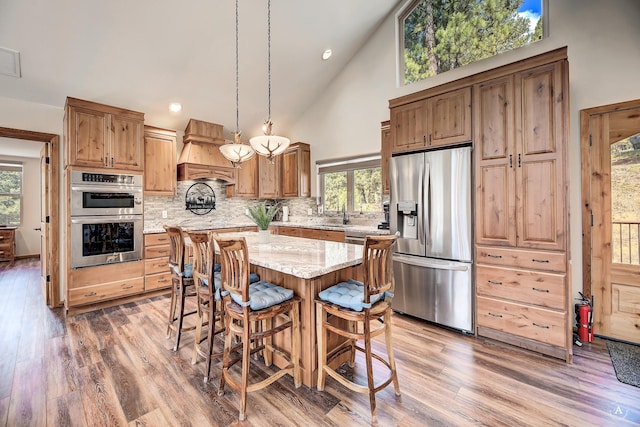 617 Mcclellan Creek Rd, Clancy, MT 59634 - kitchen featuring stainless steel appliances, custom exhaust hood, high vaulted ceiling, backsplash, and a center island