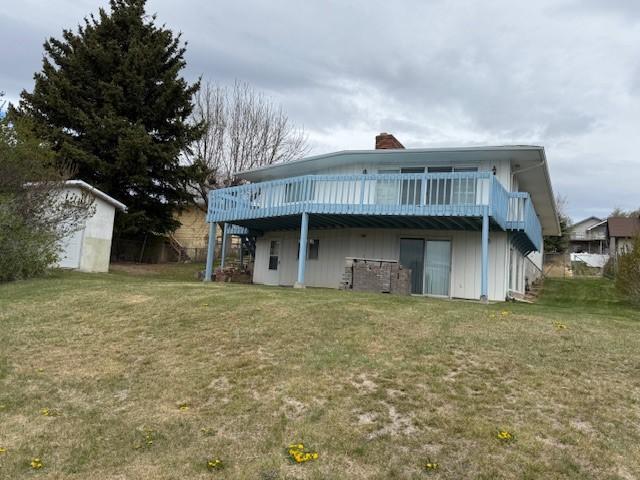 120 29th Ave NW, Great Falls, MT 59404 - rear view of house featuring a chimney, a lawn, a wooden deck, an outdoor structure, and a storage shed
