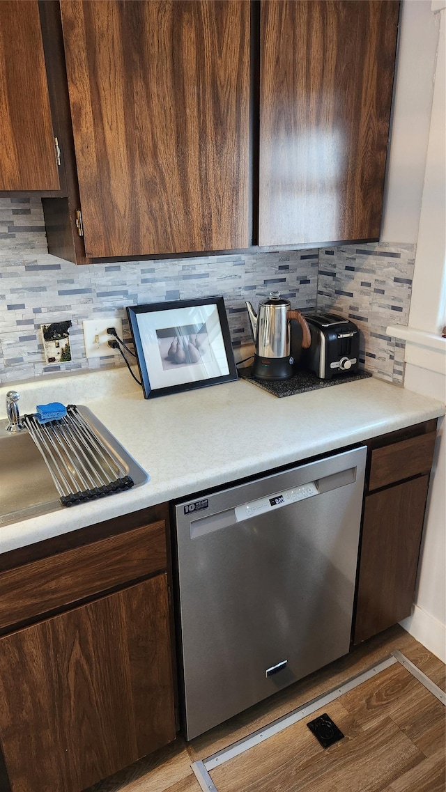 kitchen with stainless steel dishwasher, light countertops, light wood-type flooring, and decorative backsplash