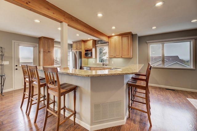 710 Joslyn St, Helena, MT 59601 - kitchen with stainless steel appliances, a breakfast bar area, light stone countertops, light wood-type flooring, and recessed lighting
