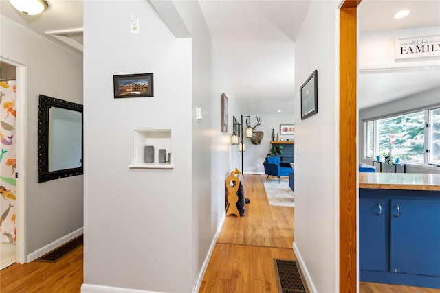 hallway featuring light wood finished floors, baseboards, and recessed lighting