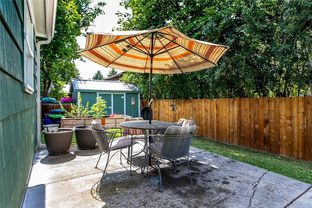 view of patio / terrace featuring outdoor dining area, a fenced backyard, an outdoor structure, and a shed