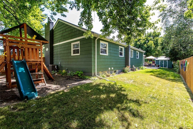 back of house featuring a playground, a storage unit, central AC unit, an outdoor structure, and a chimney