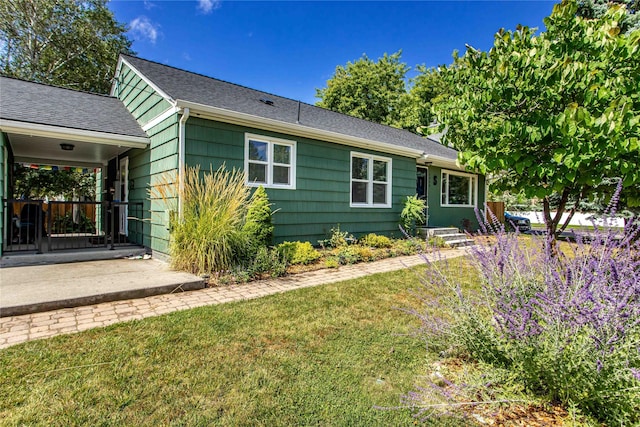 rear view of house with a lawn and a shingled roof