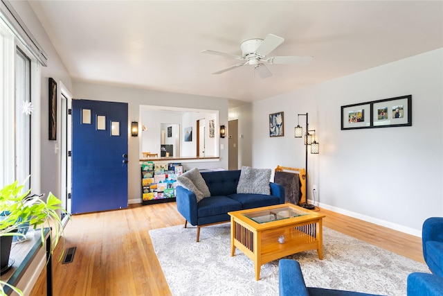 living room featuring light wood-style floors, ceiling fan, and baseboards