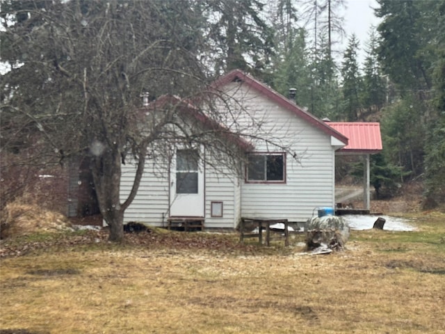 back of house with entry steps, metal roof, and a lawn