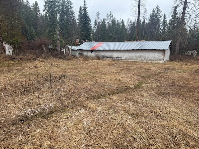 view of yard with an outbuilding, a pole building, and a wooded view