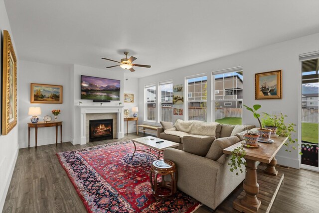 203 Kismet Ct, Hamilton, MT 59840 - living room featuring a lit fireplace, ceiling fan, wood finished floors, and baseboards