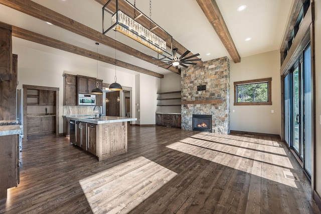112 Trading Post Trl, Bigfork, MT 59911 - unfurnished living room featuring beamed ceiling, a fireplace, dark wood-style flooring, a sink, and a ceiling fan