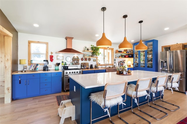 33766 W Shore Dr, Polson, MT 59860 - kitchen featuring stainless steel appliances, open shelves, wall chimney range hood, blue cabinets, and light countertops