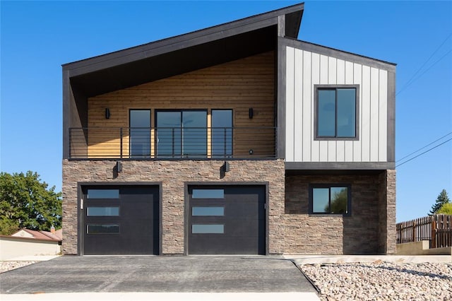 861 9th St W, Kalispell, MT 59901 - modern home featuring stone siding, an attached garage, driveway, and a balcony