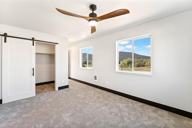 861 9th St W, Kalispell, MT 59901 - unfurnished bedroom with a barn door, carpet flooring, a closet, a spacious closet, and ceiling fan