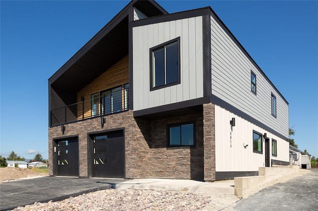 861 9th St W, Kalispell, MT 59901 - view of front of property featuring stone siding, a garage, and a balcony