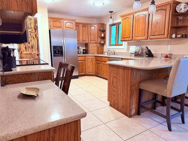 kitchen with stainless steel fridge with ice dispenser, open shelves, a peninsula, brown cabinetry, and a textured ceiling