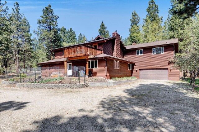 303 Wyant Ln, Hamilton, MT 59840 - view of front of house featuring a chimney, an attached garage, dirt driveway, and fence