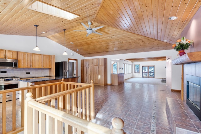 303 Wyant Ln, Hamilton, MT 59840 - kitchen featuring appliances with stainless steel finishes, a tiled fireplace, open floor plan, decorative backsplash, and ceiling fan