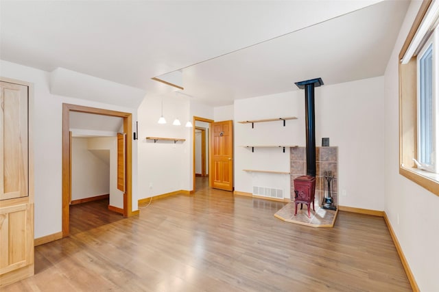 303 Wyant Ln, Hamilton, MT 59840 - unfurnished living room with a wood stove, light wood finished floors, and baseboards