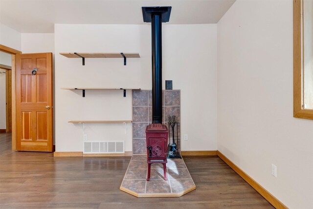 303 Wyant Ln, Hamilton, MT 59840 - unfurnished living room featuring a wood stove, wood finished floors, and baseboards
